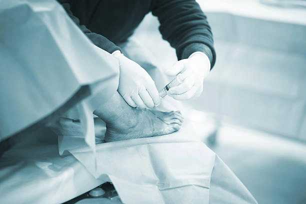 Doctor Román Cañada realizando una infiltración en el tobillo como tratamiento para el dolor articular en consulta especializada en Sevilla y Huelva